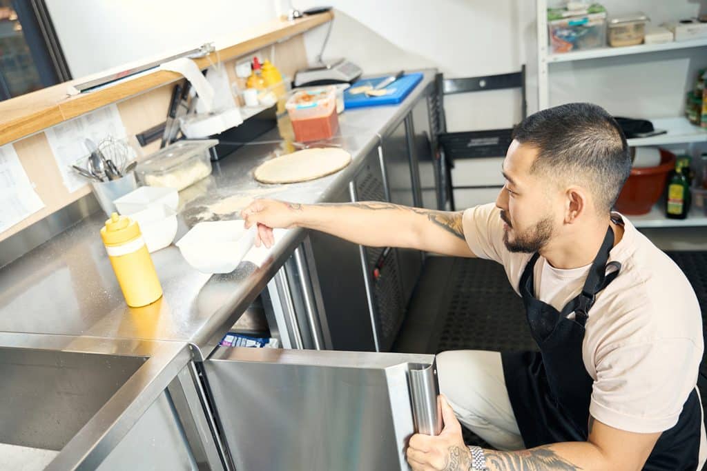 Asian guy in apron preparing his kitchen for a cook off